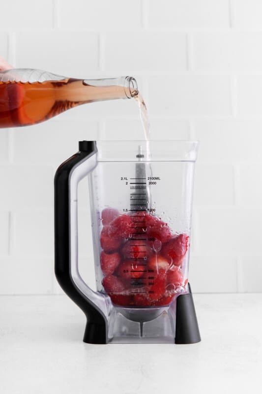 pouring rosé into a blender or frozen strawberries