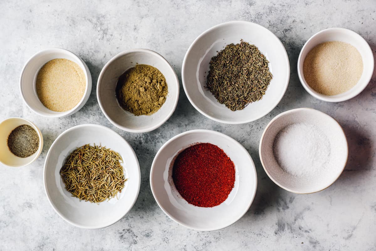 Overhead view of ingredients for turkey rub in white bowls.