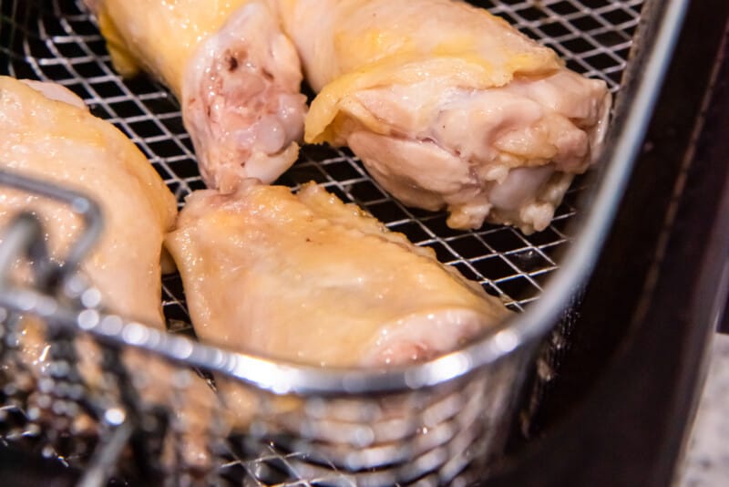 chicken wings in a deep fryer basket.