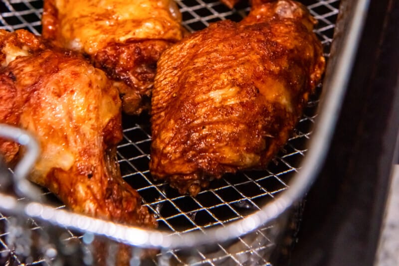 trashed wings in a deep fryer basket.