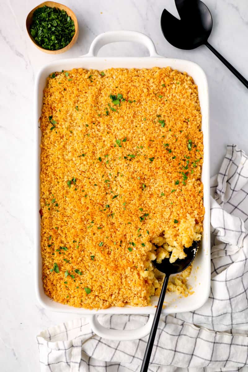 overhead view of mac and cheese casserole in a white baking pan with a black serving spoon.