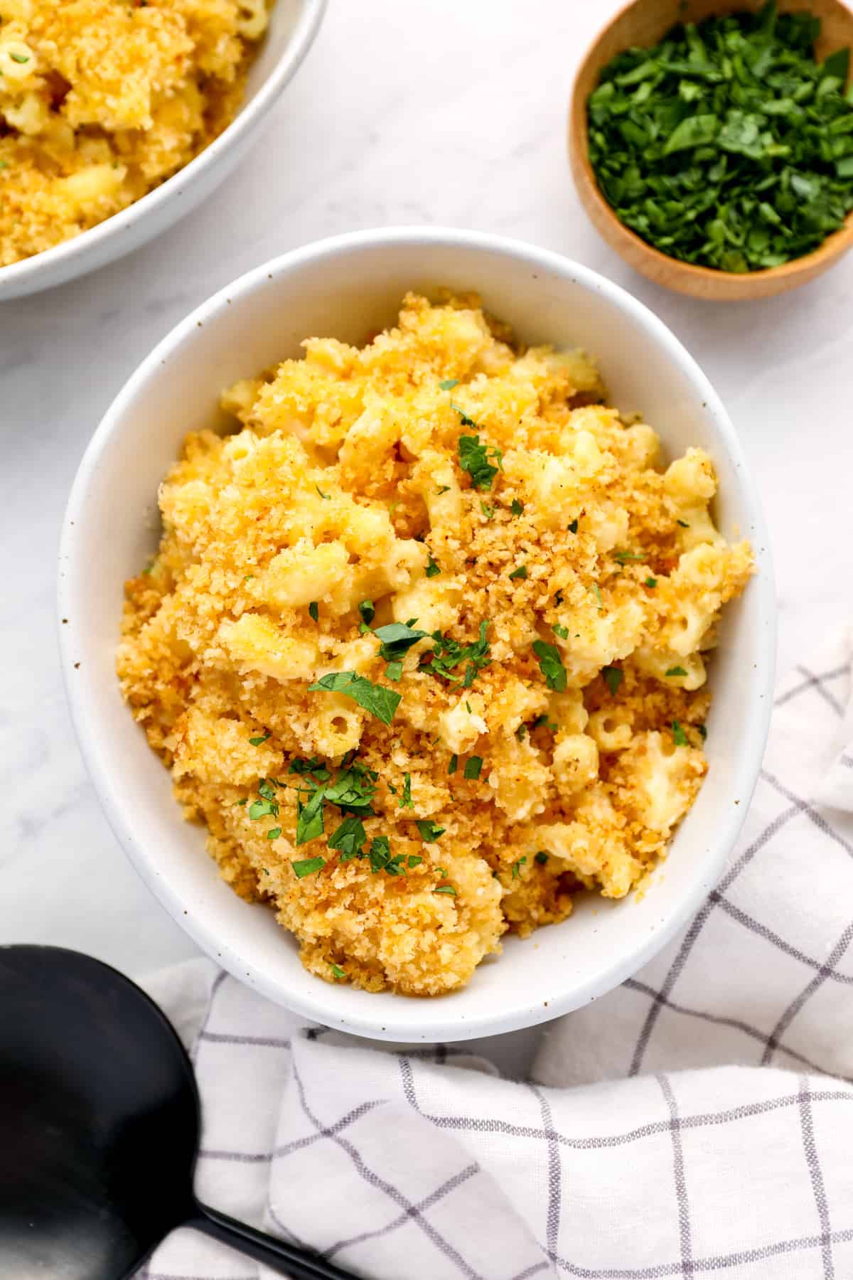 a serving of mac and cheese casserole in a white bowl with parsley.