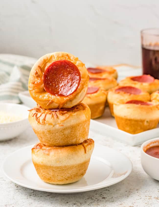 a turned pizza cupcake stacked on 2 upright pizza cupcakes on a white plate.