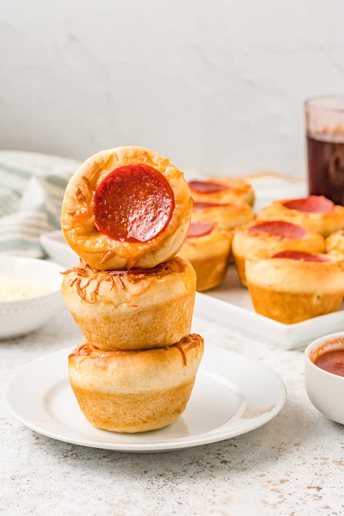 a turned pizza cupcake stacked on 2 upright pizza cupcakes on a white plate.