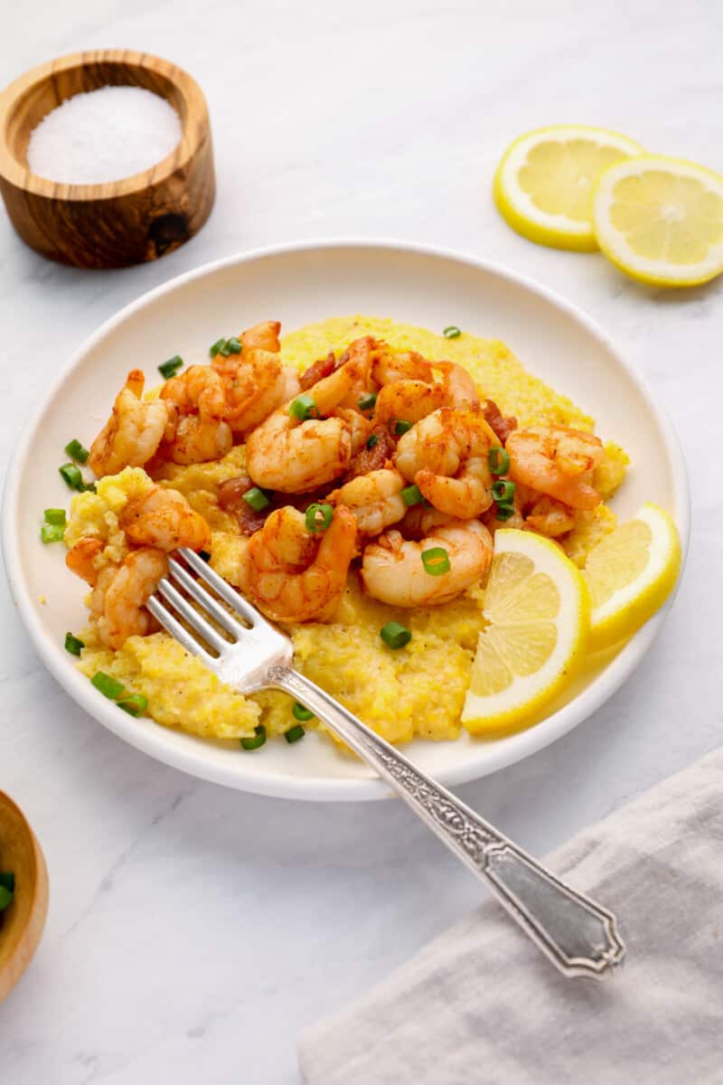 cheesy grits and cajun style shrimp on a plate with a fork