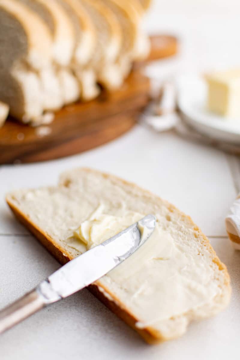 butter knife spreading butter onto a slice of skillet bread