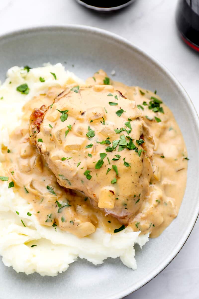 close up on a plate of smothered pork chops with mashed potatoes