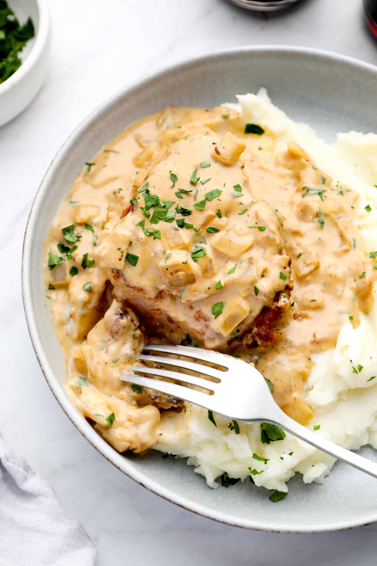 smothered pork chops in a bowl of mashed potatoes