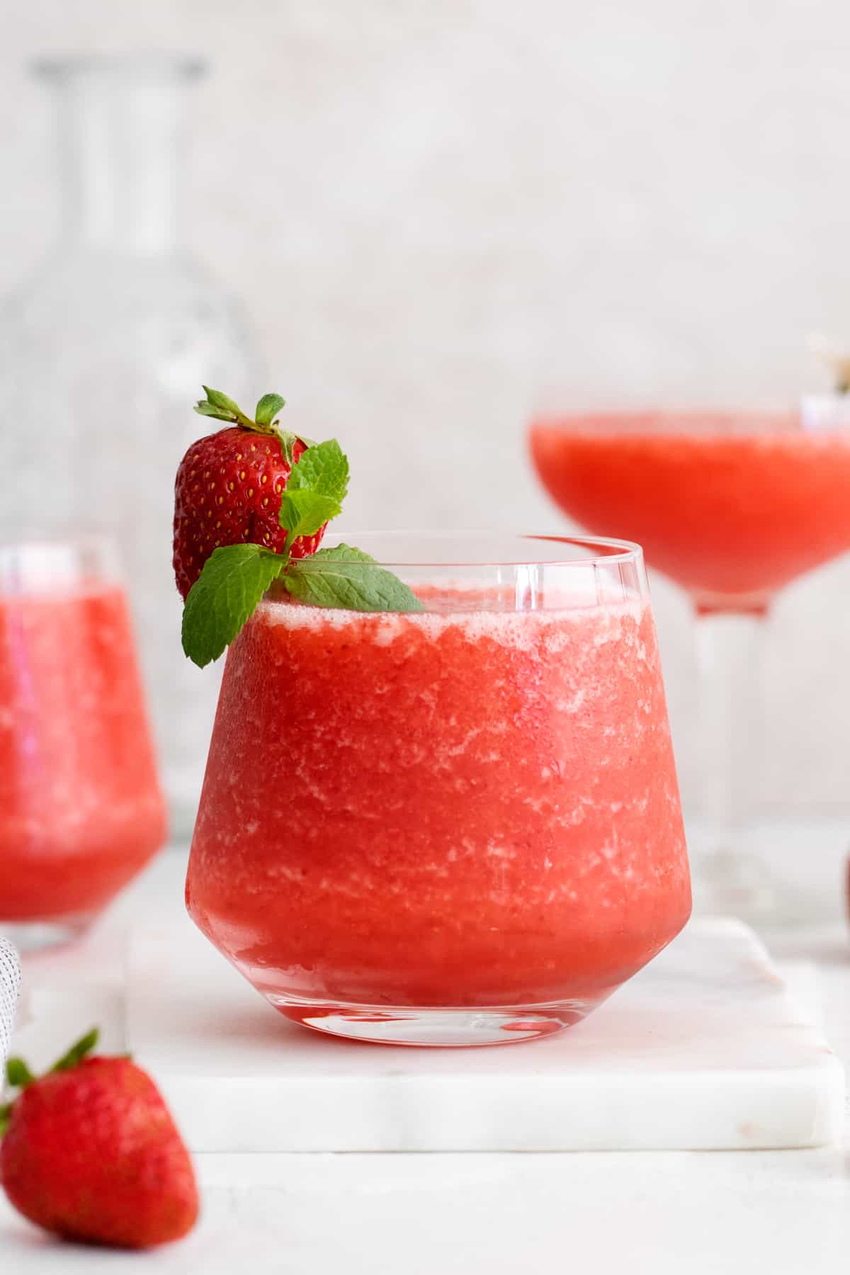 a glass of strawberry frose, garnished with a fresh strawberry