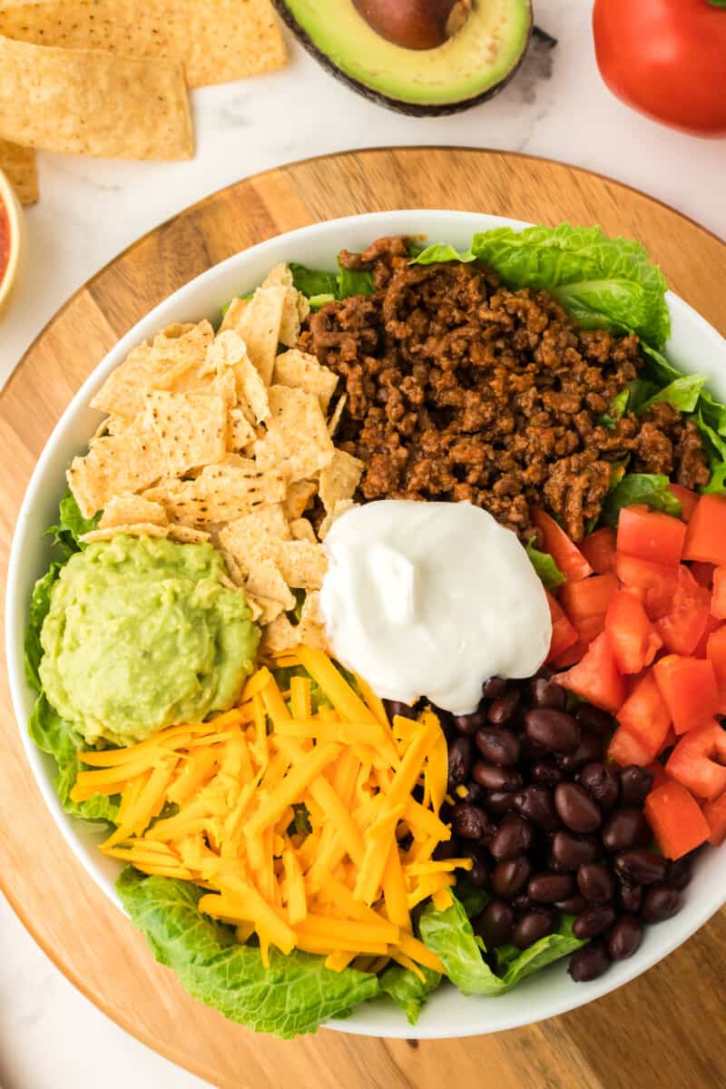 homemade taco salad, with ingredients grouped together on top of greens