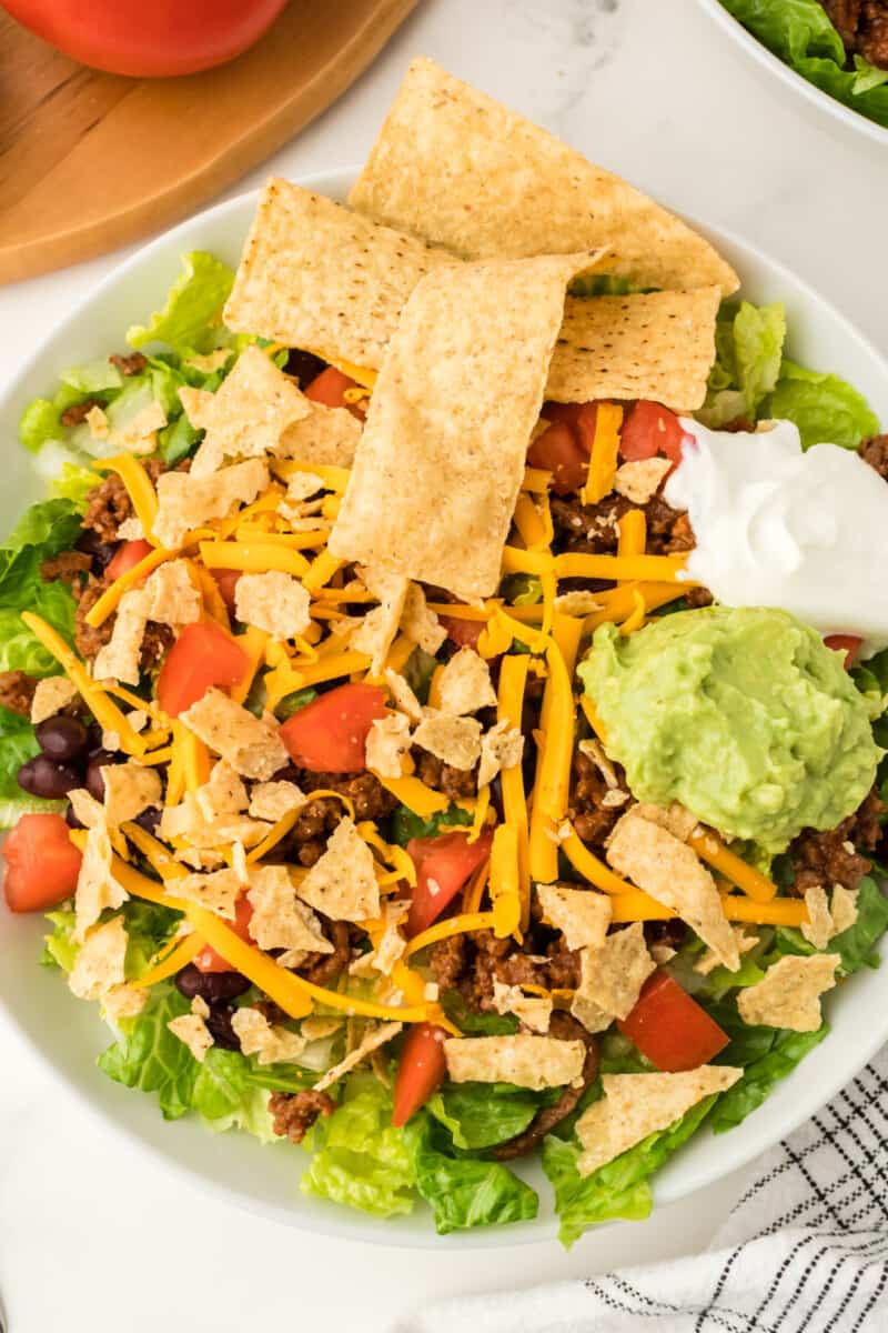 green salad topped with ground beef, cheese, tomatoes, tortilla strips, beans, and more