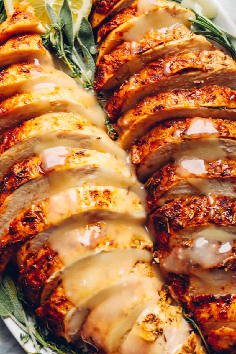 close up of sliced thanksgiving turkey breasts on a white serving platter.