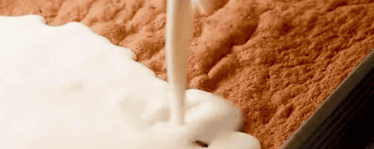 Pouring the milk mixture over the cake.