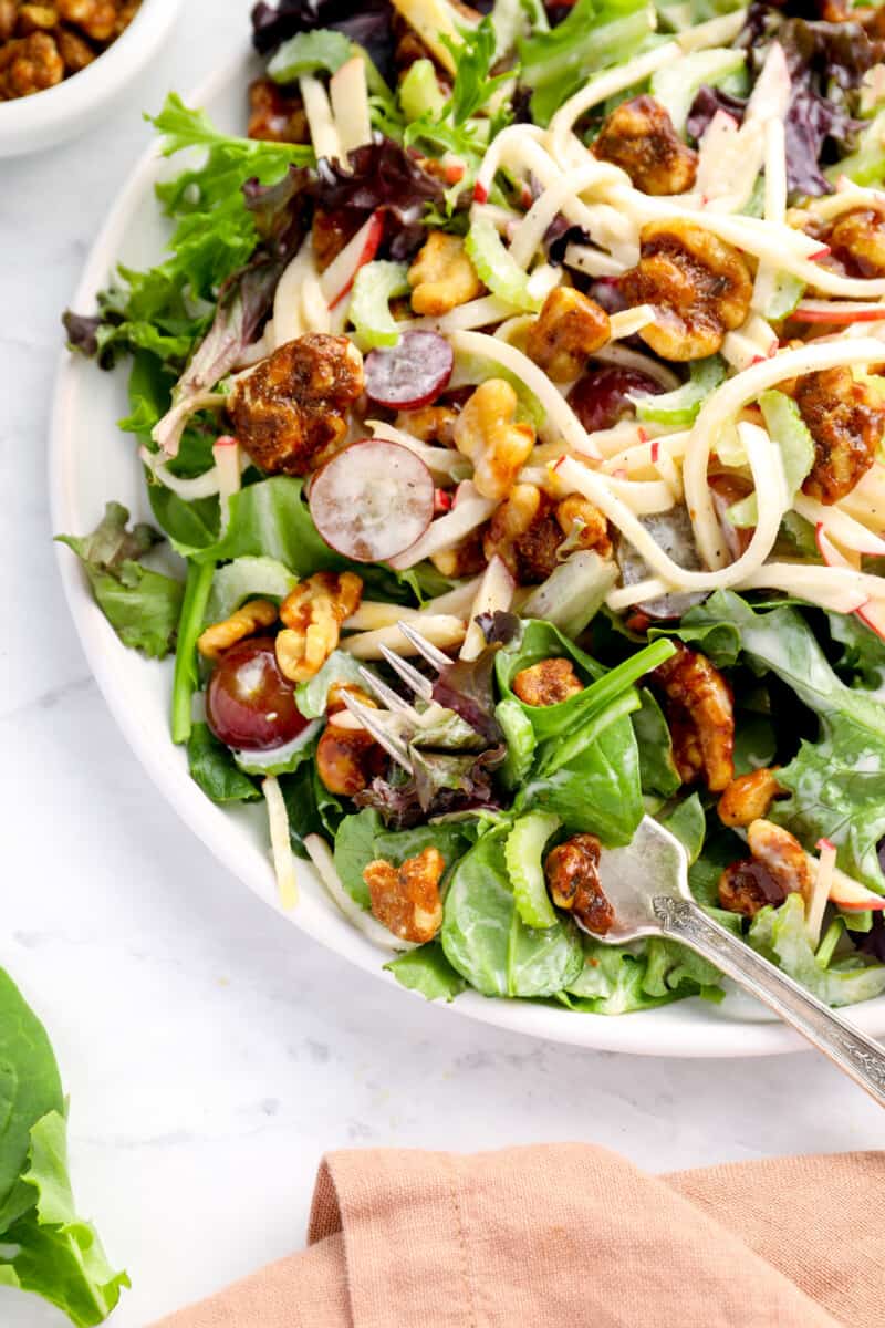 close up on a bowl of salad topped with grapes and walnuts