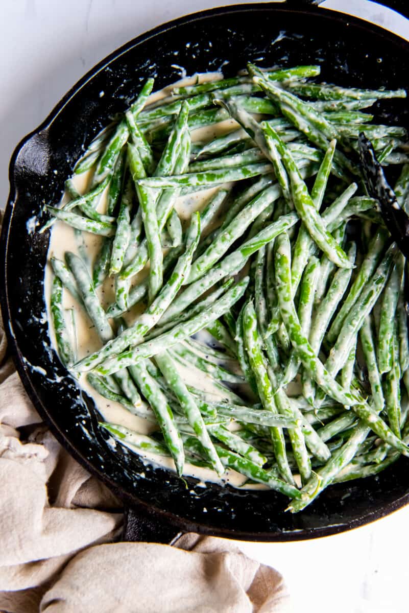overhead view of creamed green beans in a cast iron skillet.