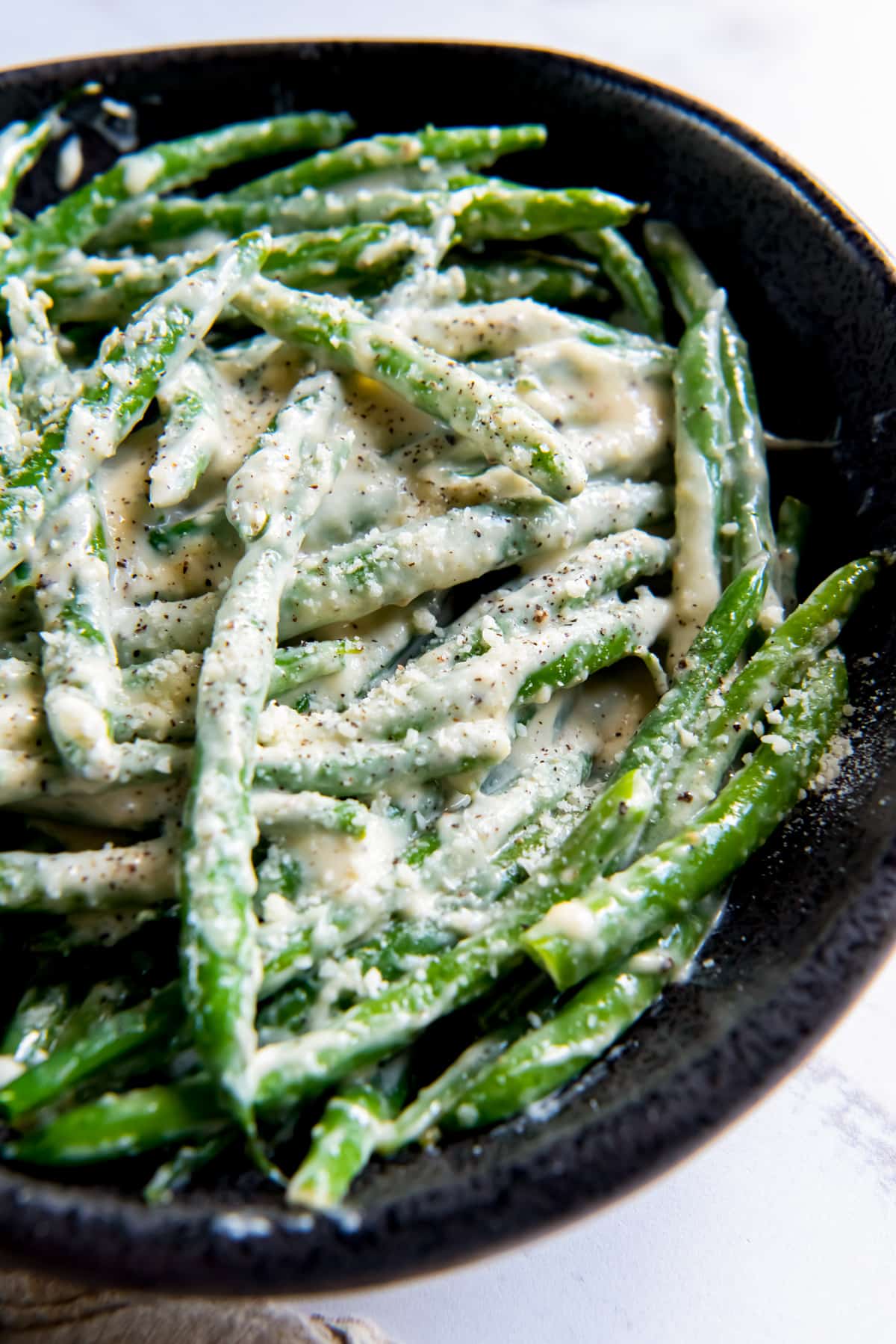 creamed green beans in a black serving bowl.