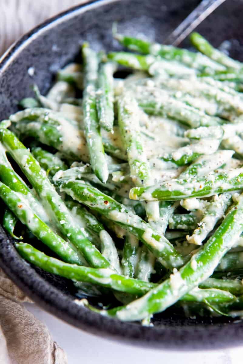 creamed green beans in a black serving dish with a spoon.
