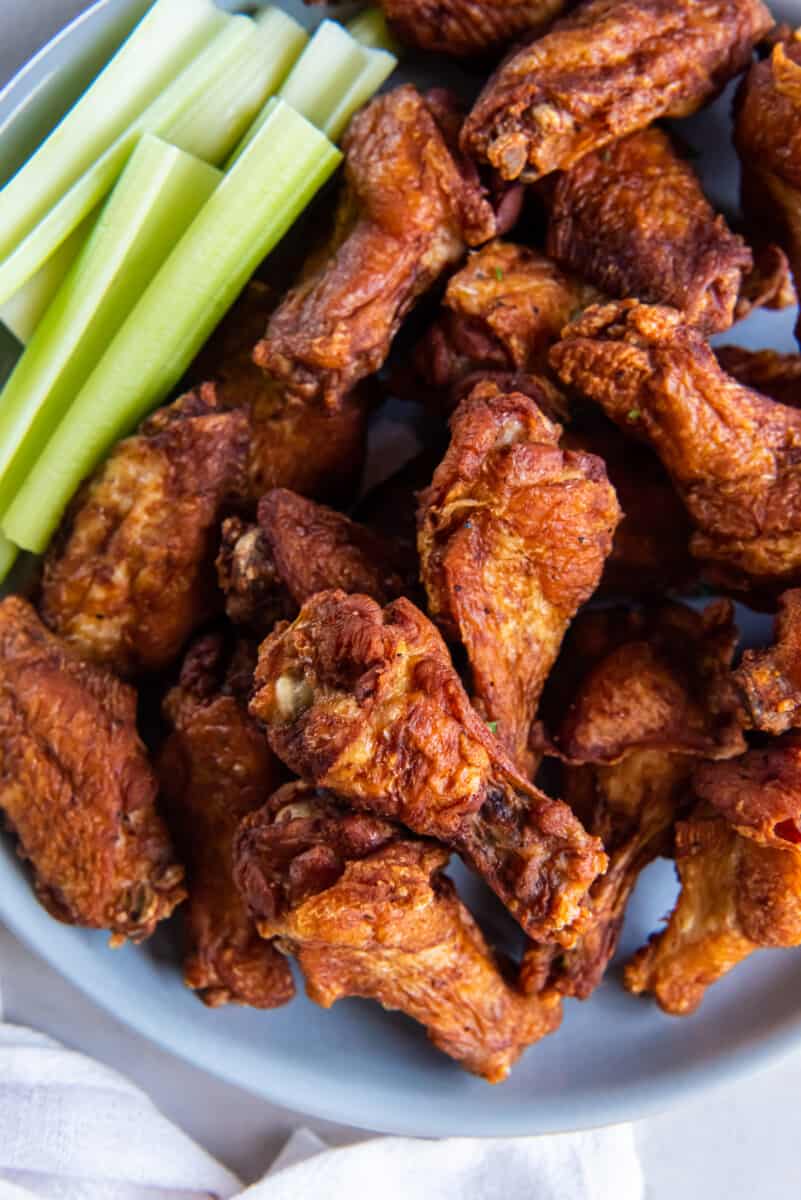 close up of trashed wings on a gray plate with celery sticks.