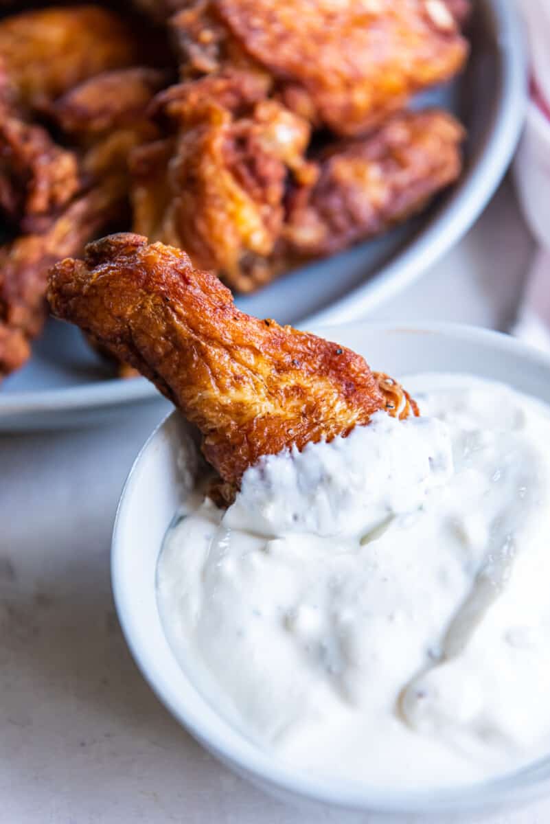 a trashed wing being dipped in a bowl of ranch.