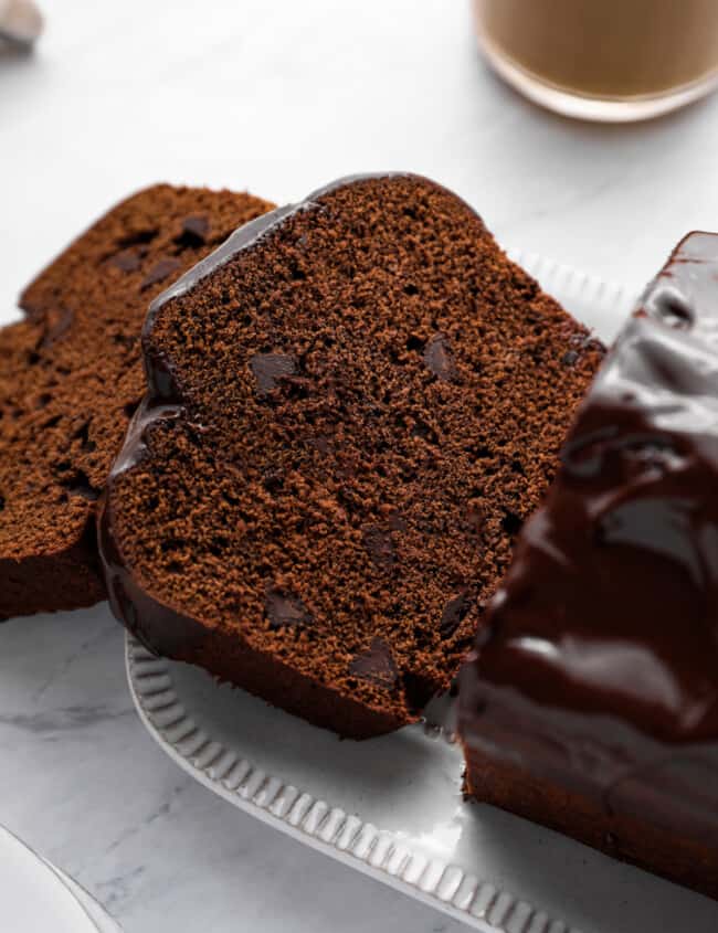close up of sliced chocolate pound cake on a white serving plate.