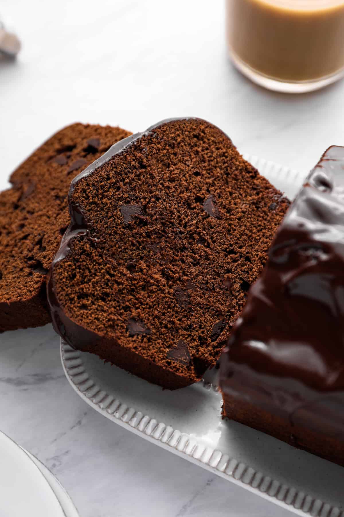 close up of sliced chocolate pound cake on a white serving plate.