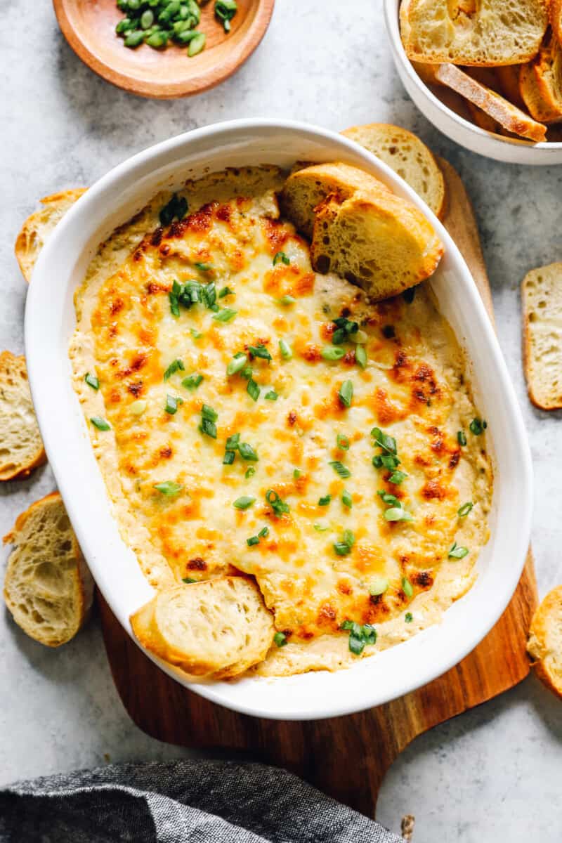 baked crab dip in a dish, surrounded by small pieces of dipping bread