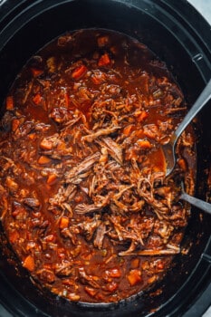 slow cooker beef ragu in a crockpot with 2 forks.