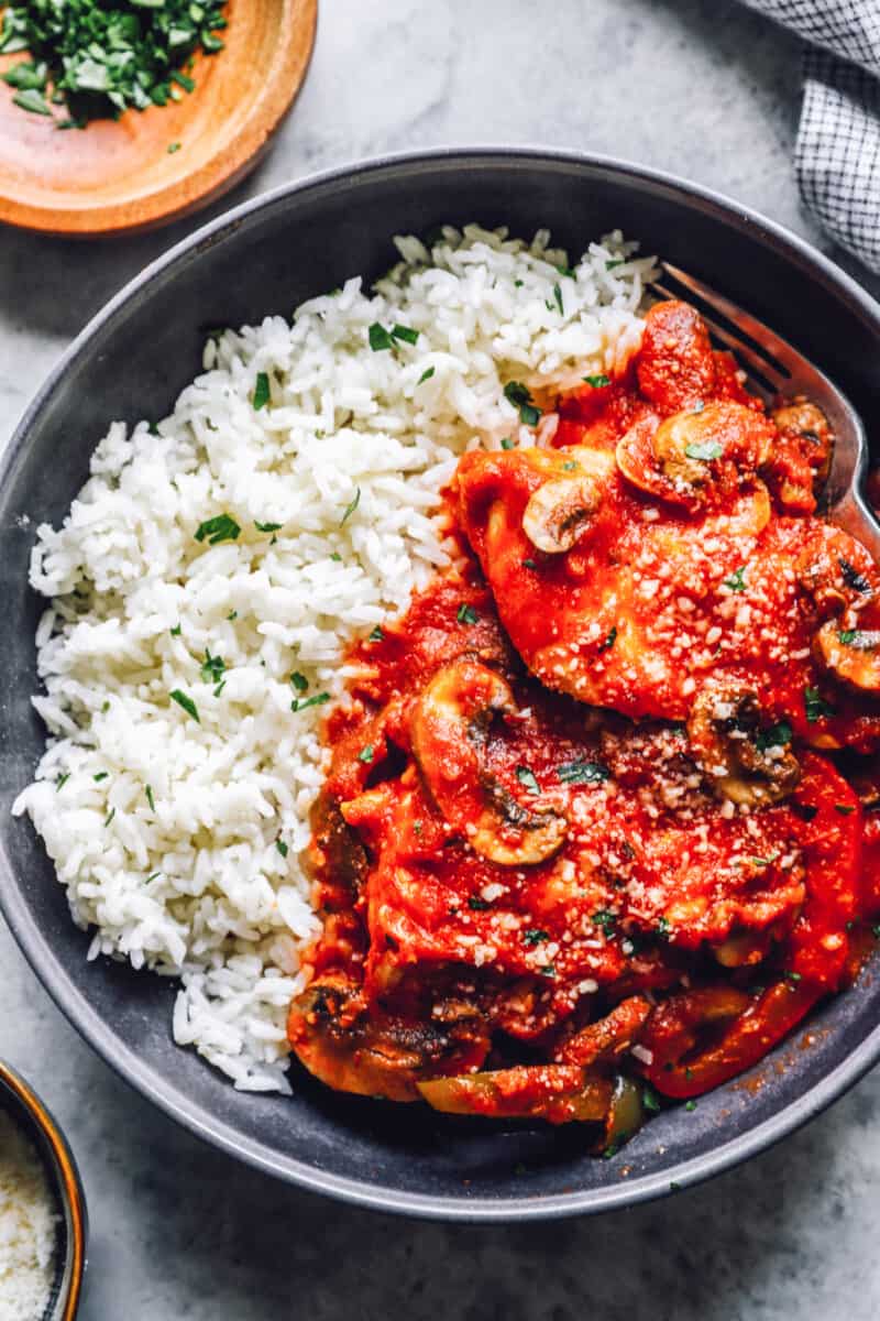 overhead view of crockpot chicken cacciatore with rice in a black bowl.