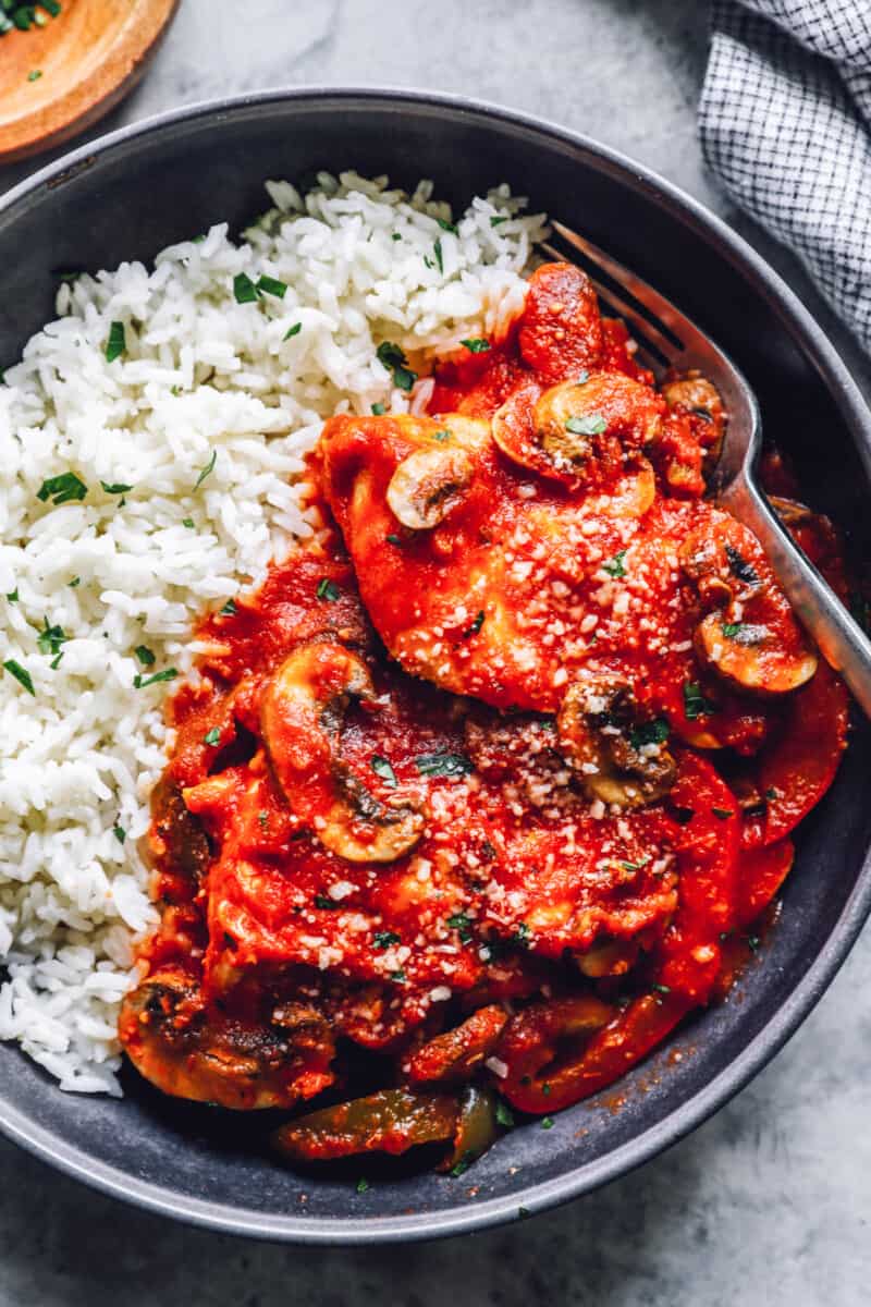 overhead view of crockpot chicken cacciatore with rice in a black bowl.