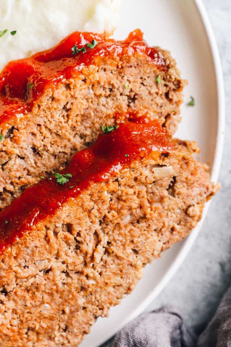 close up view of 2 slices of crockpot meatloaf on a white plate.