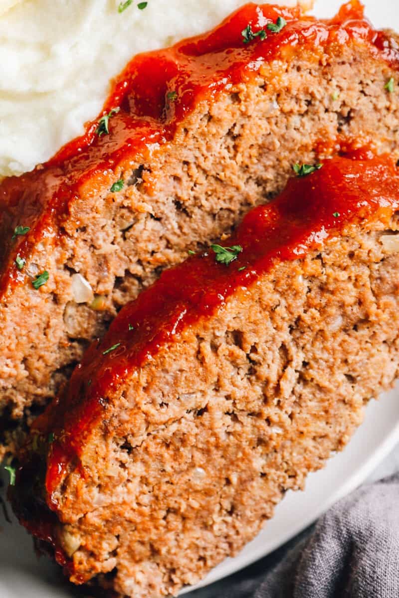 close up view of 2 slices of crockpot meatloaf on a white plate.