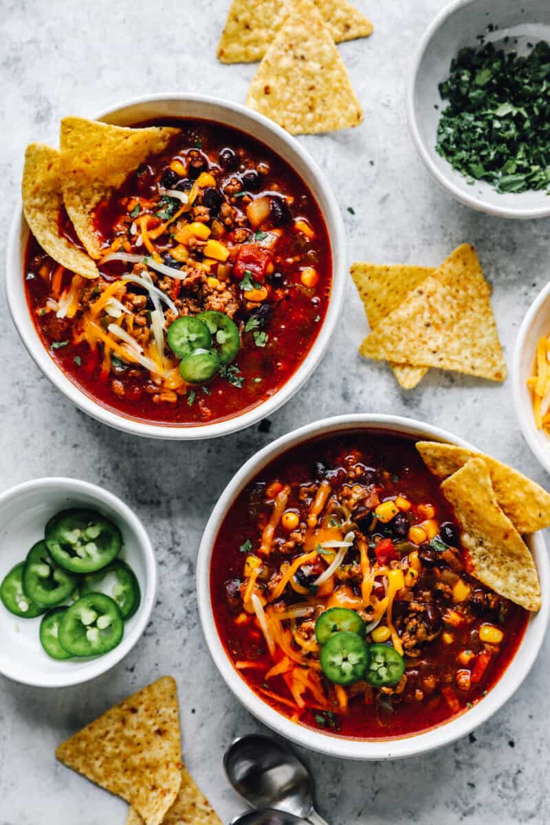 overhead view of crockpot taco soup in white bowls with tortilla chips.
