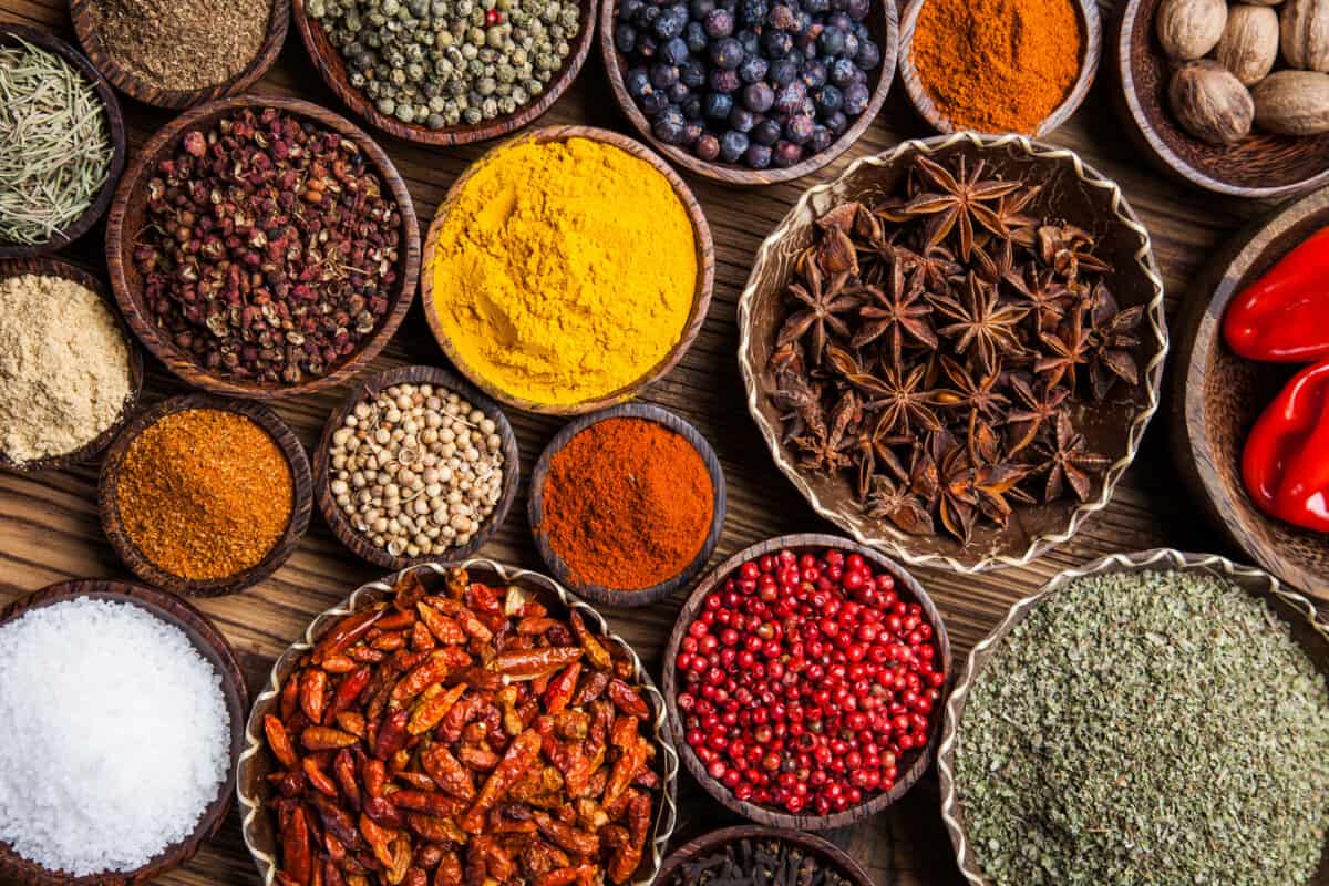 fresh, ground cooking spices and whole spices arranged in bowls.