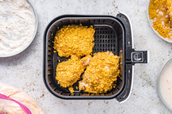 overhead view of breaded chicken pieces in an air fryer basket.