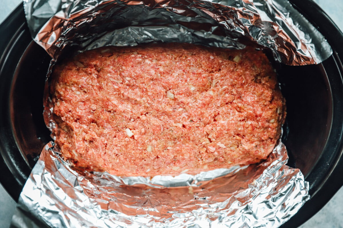 overhead view of uncooked crockpot meatloaf in a slow cooker.