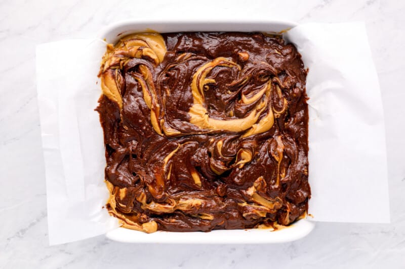 overhead view of swirled peanut butter brownie batter in a square baking pan.