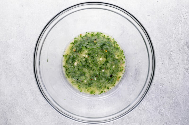 overhead view of melted butter and herbs in a glass bowl.