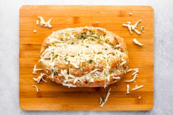 overhead view of bread stuffed with butter and cheese on a cutting board.