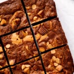 overhead view of cut peanut butter brownies on a white cutting board.