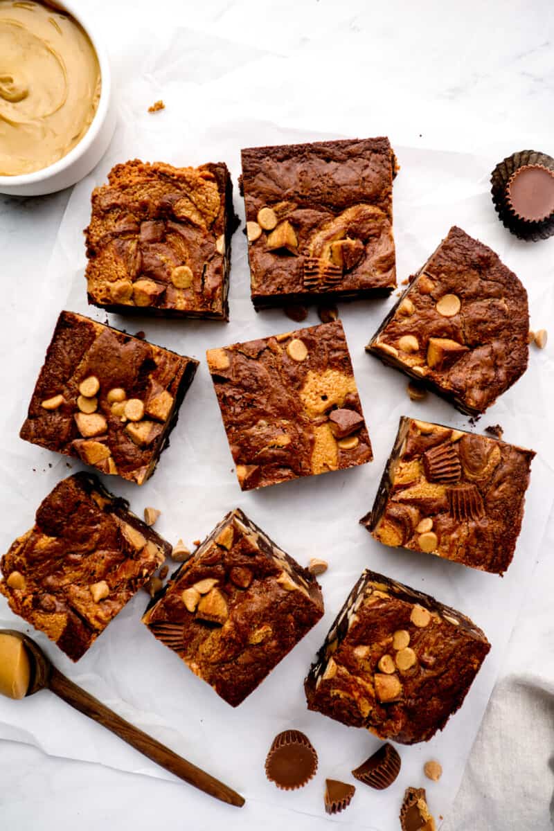 overhead view of askew cut peanut butter brownies on a white cutting board.