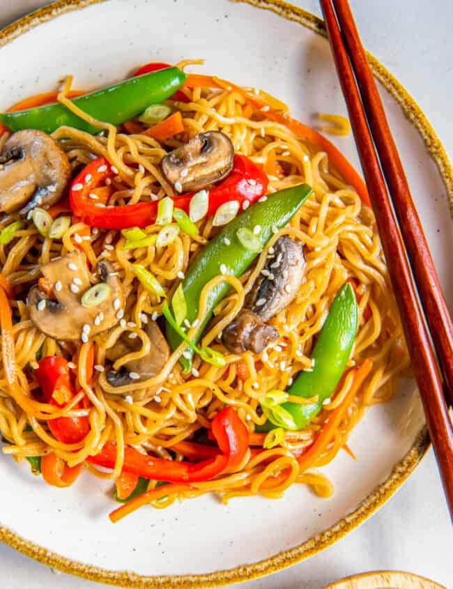 overhead view of vegetable lo mein on a white plate with chopsticks.