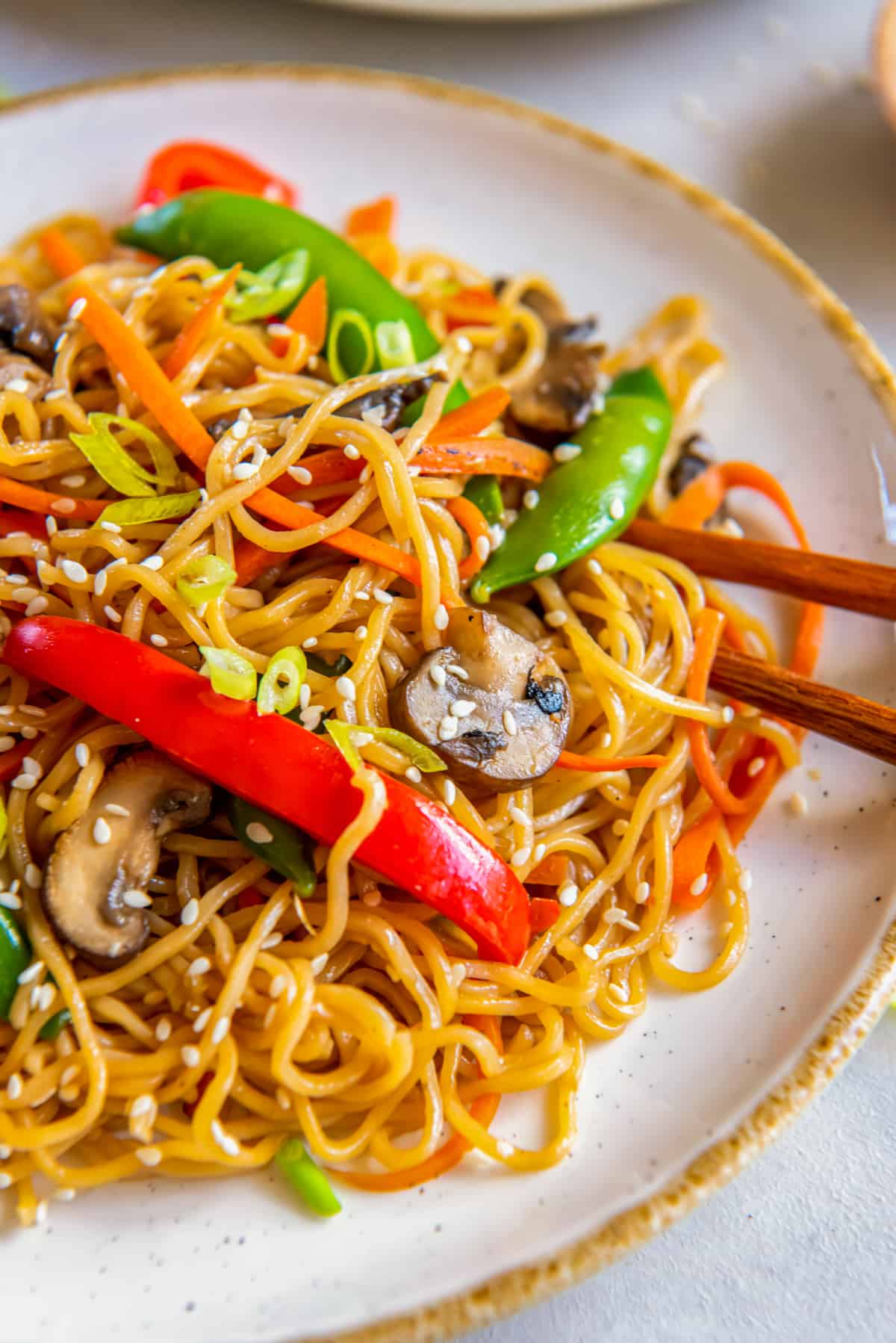 vegetable lo mein on a white plate with chopsticks.