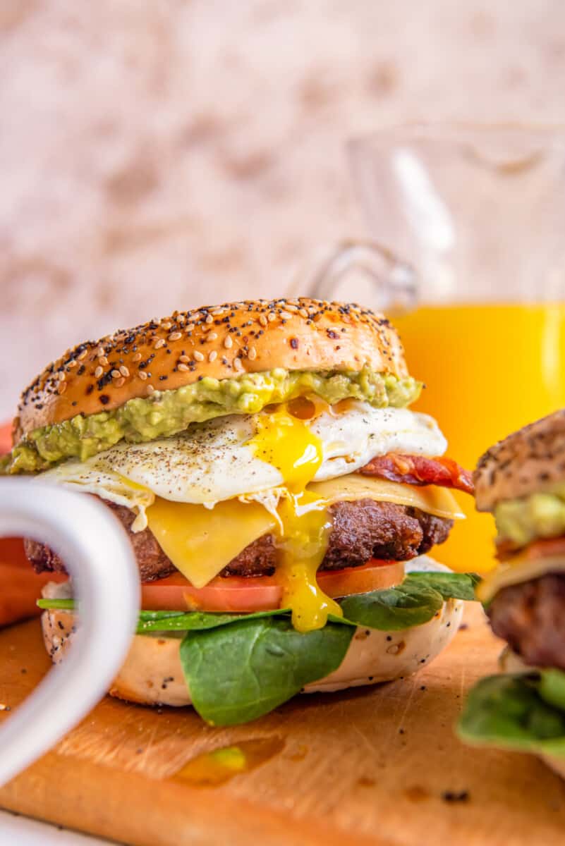 close up of a breakfast burger on a wooden cutting board.