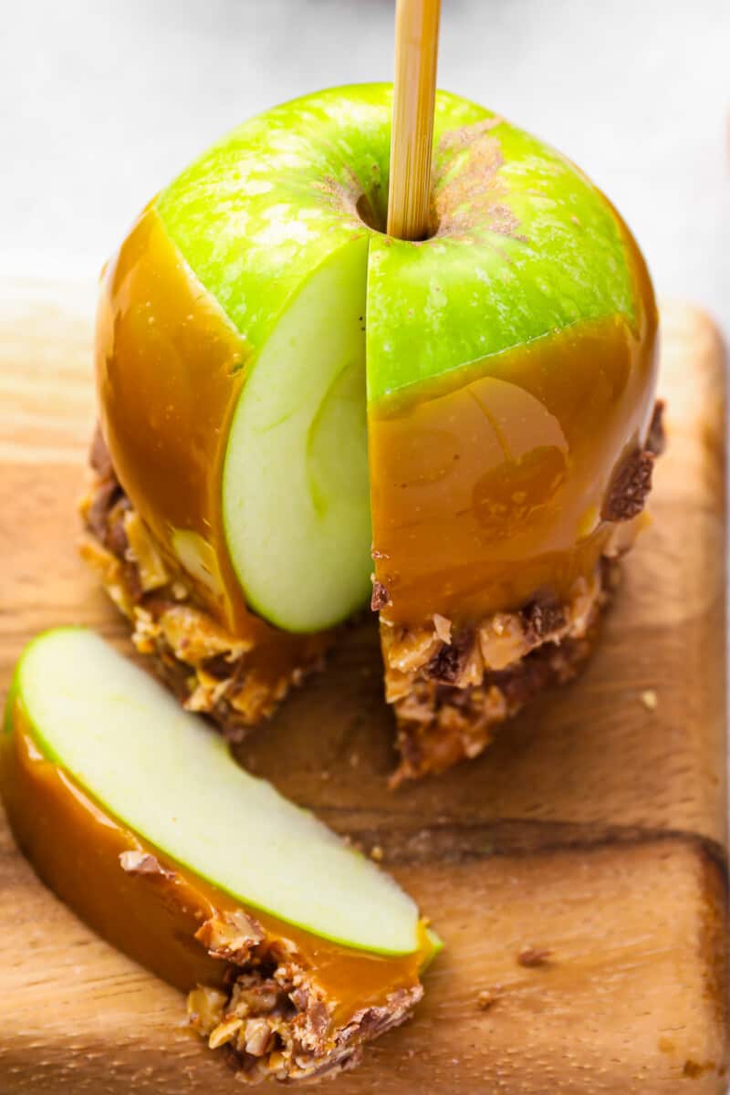 close up on a caramel apple, with one slice cut out to show the interior