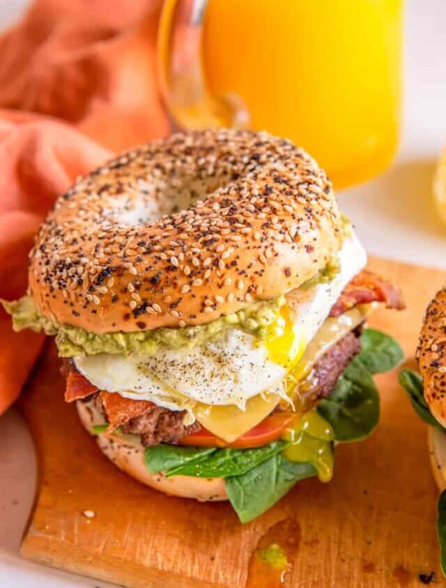 close up of a breakfast burger on a wooden cutting board.