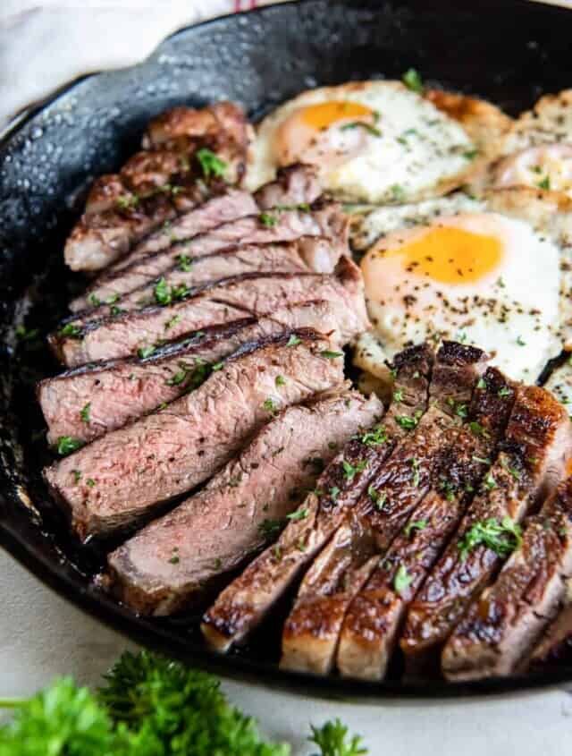 close up view of steak and eggs in a cast iron pan.