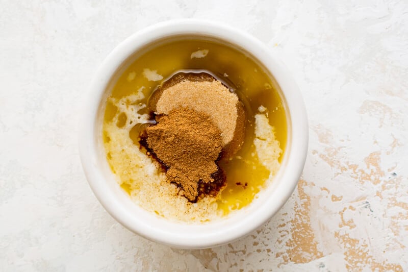cinnamon powder in a bowl on a white surface.