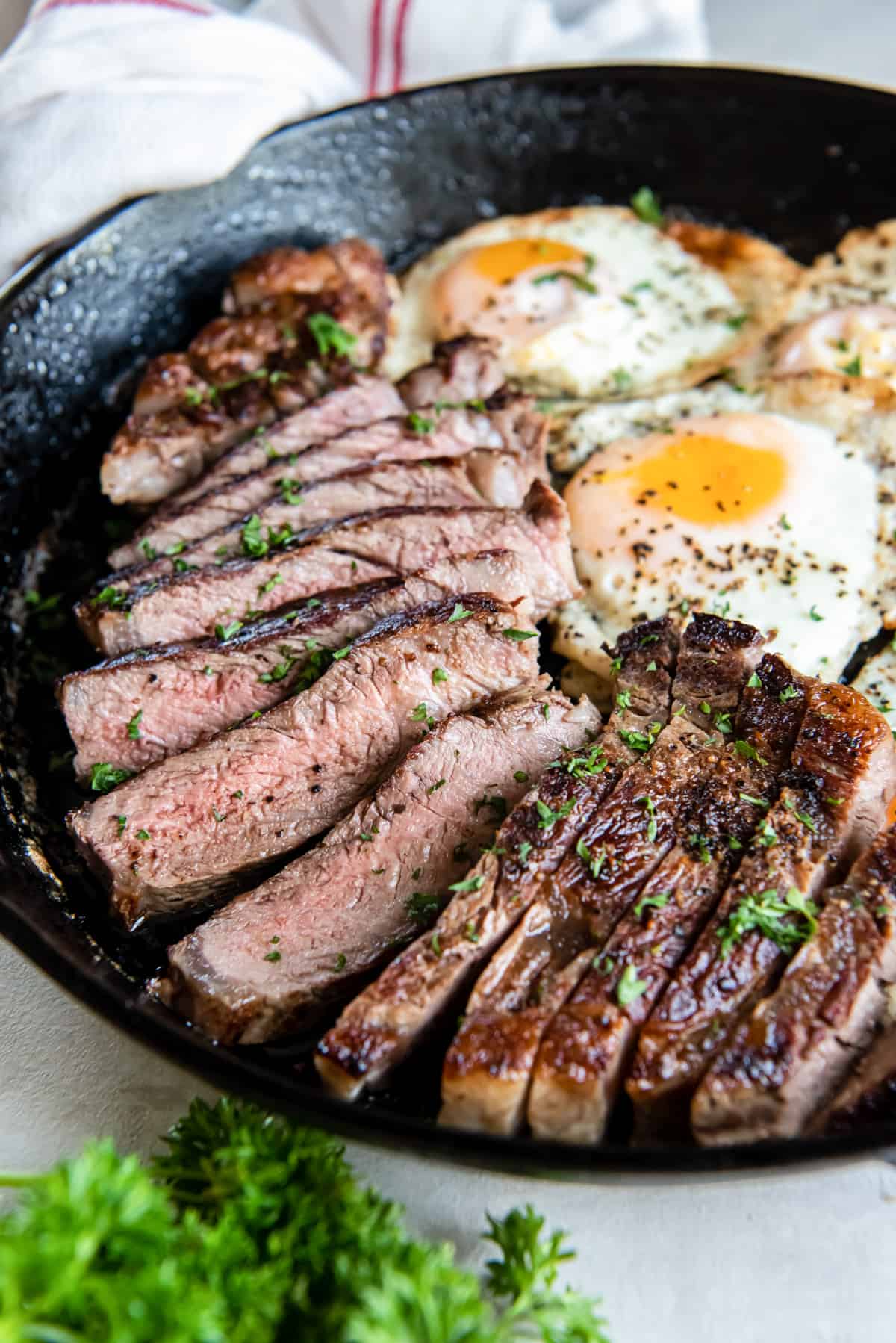 close up view of steak and eggs in a cast iron pan.