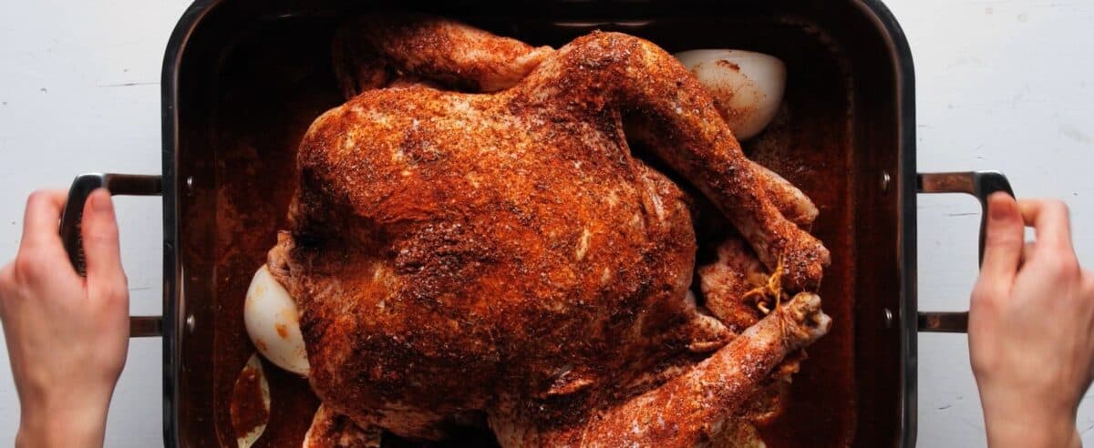 Seasoned turkey with the legs tired in a casserole pan with onions and bay leaves.