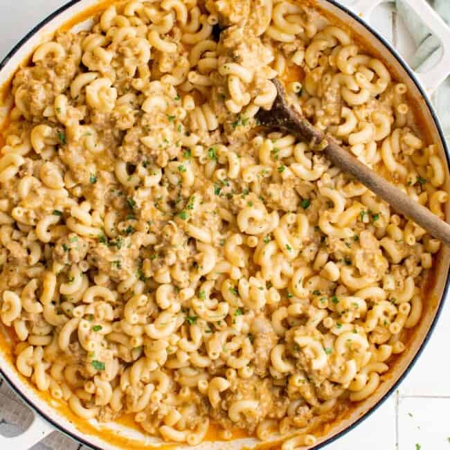 overhead view of hamburger helper in a white pan with a wooden spoon.